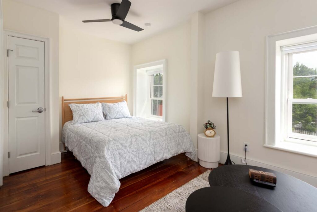 Cozy bedroom corner in Frontier House Airbnb suite featuring plush bedding, soft pillows, and warm lighting that invites relaxation after a romantic evening in Lewiston, NY.