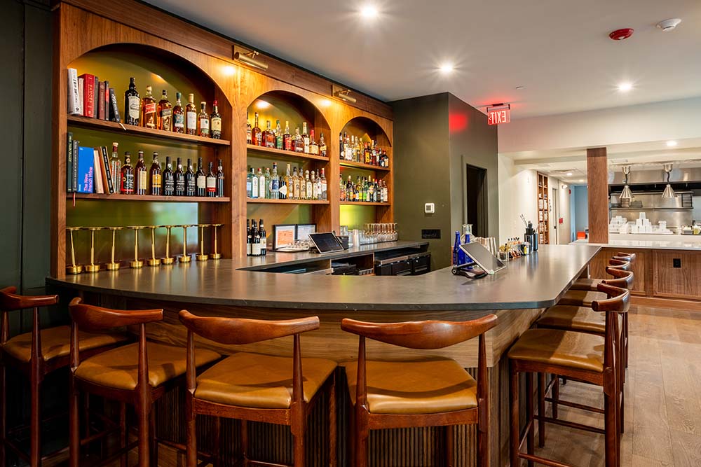 Elegant bar at The Fairbanks restaurant inside Frontier House, featuring polished wood counters, ambient lighting, and craft cocktails perfect for romantic evenings in historic Lewiston, NY.